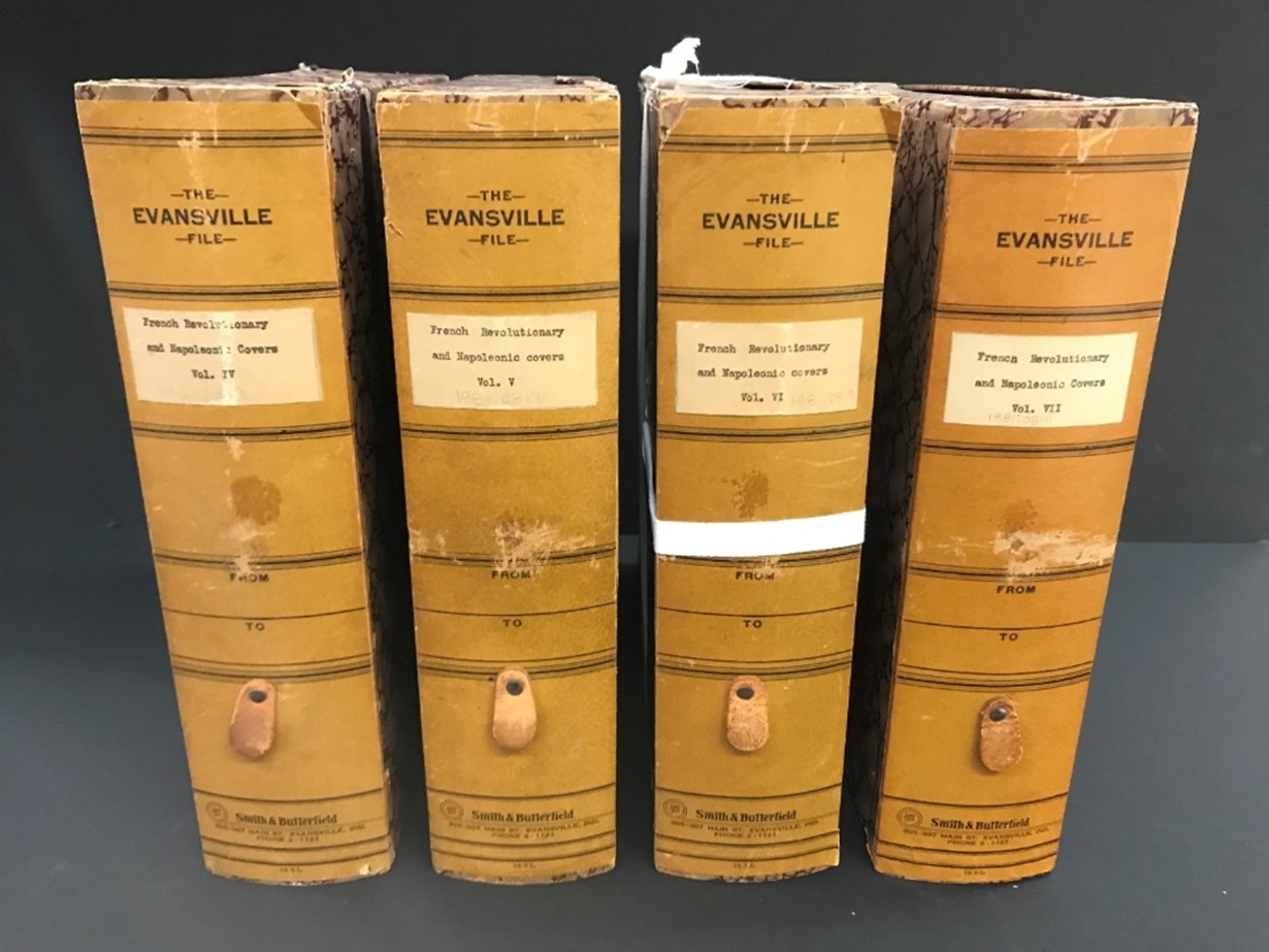 Photograph of four books standing up in a row with yellow-tan binding 