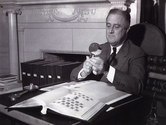 Franklin D. Roosevelt looking at a stamp through a magnifying glass