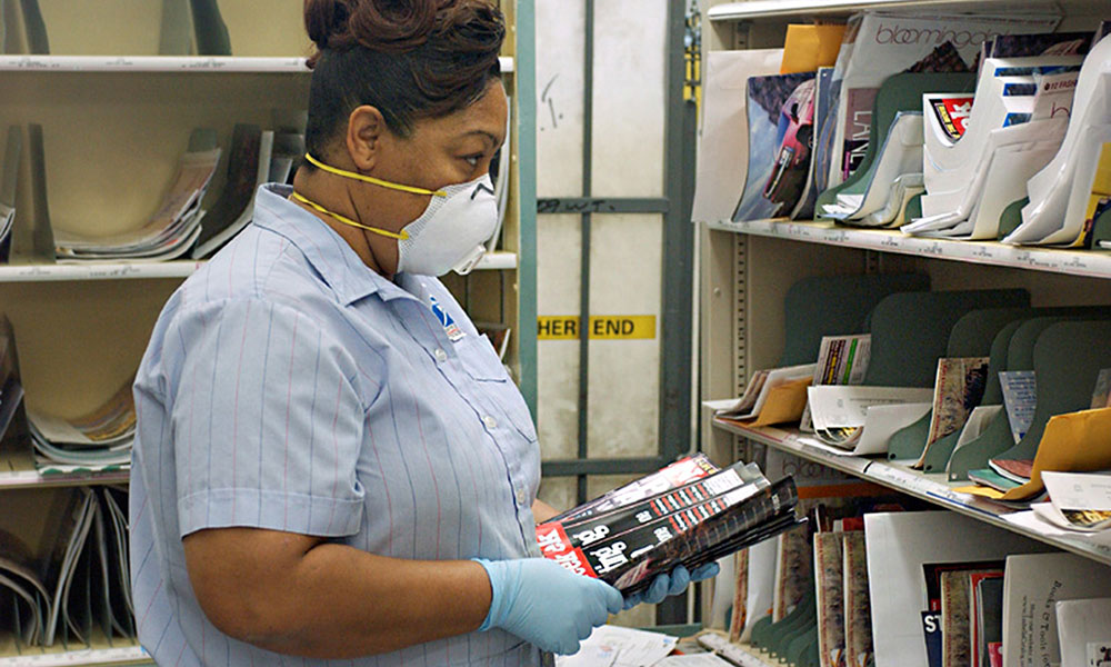 Postal worker wearing rubber gloves while sorting mail