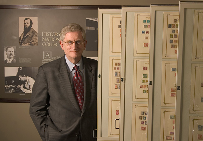 photo of W. Wilson Hulme II next to a display of stamp sheets