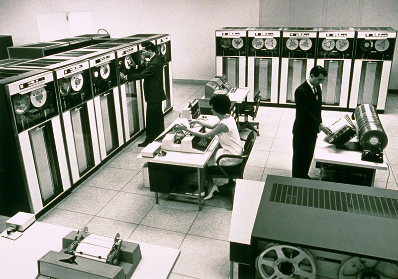 Three people working in a room full of computer equipment