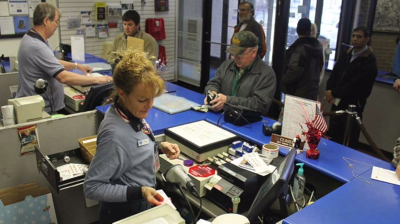Customers and two USPS staff working in a post office