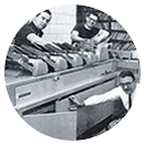 Three men working with a mail inserter machine.