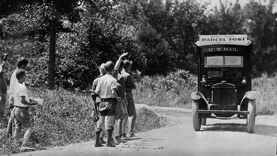 A groups of boys watching an oncoming Parcel Post truck