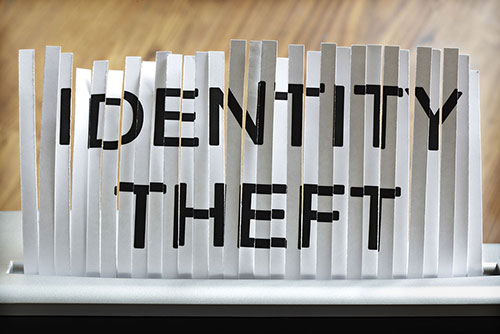 Paper shredder shredding a document that reads, 'identity theft'.