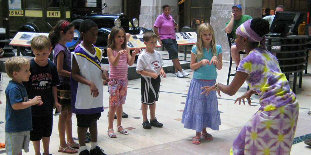 Volunteer storyteller interacting with young people in the museum's Atrium